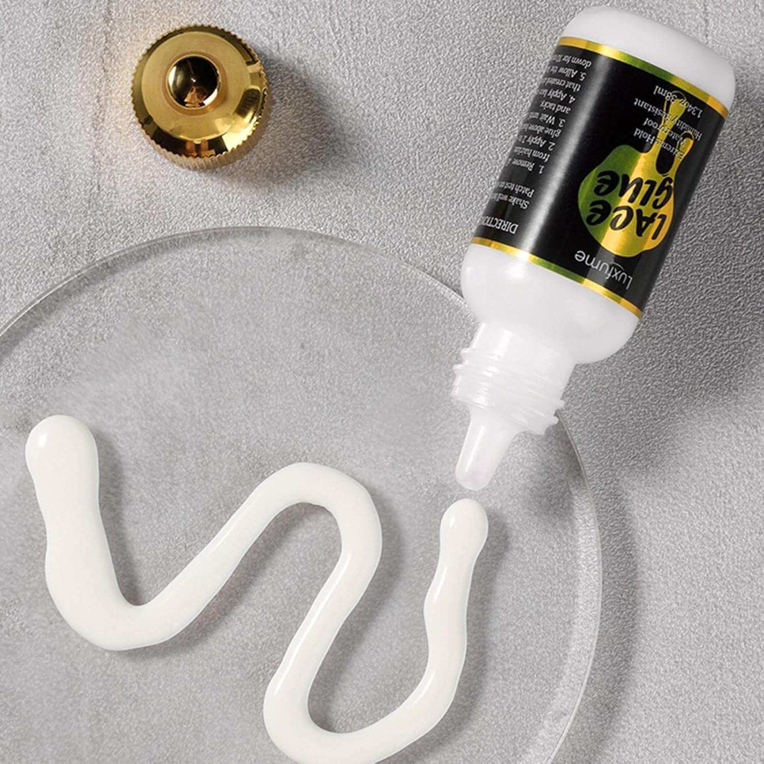 Luxfume Waterproof Strong Hold Lace Adhesive/Glue - 1.28oz on a glass surface with a swirl of adhesive.