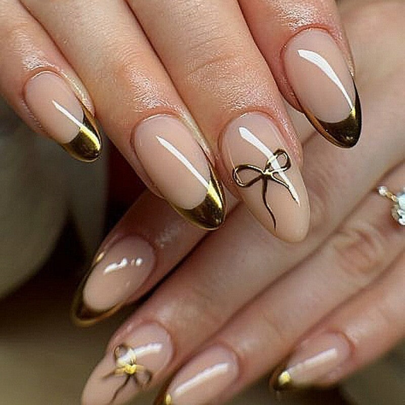 Hand wearing Nude & Gold Chrome French Almond with Bows press-on nails